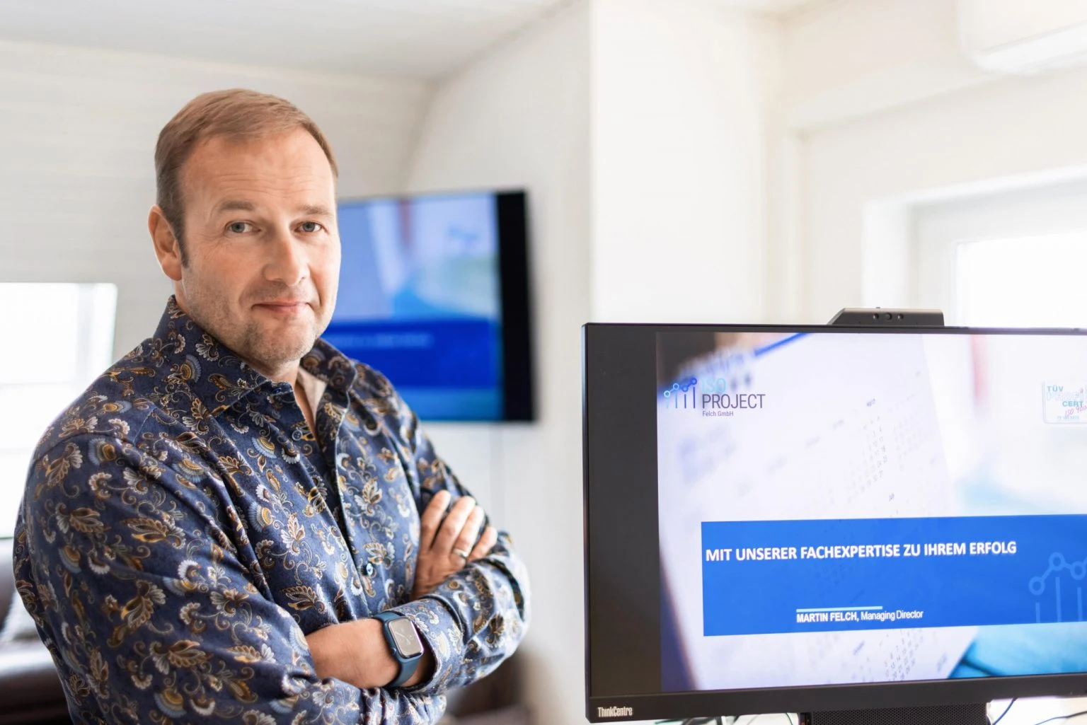 Martin Felch, Gesch&auml;ftsf&uuml;hrer der ISO Project Felch GmbH, vor einem Bildschirm mit Firmenpr&auml;sentation