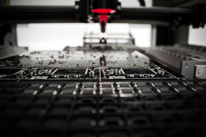 Nahaufnahme einer Leiterplatte während der Bestückung durch eine SMD-Bestückungsmaschine